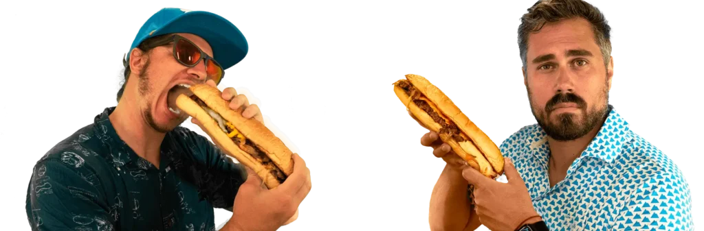 Eric Sollenberger on the left taking a bite of a cheesesteak, and Dan Katz on the right holding a cheesesteak
